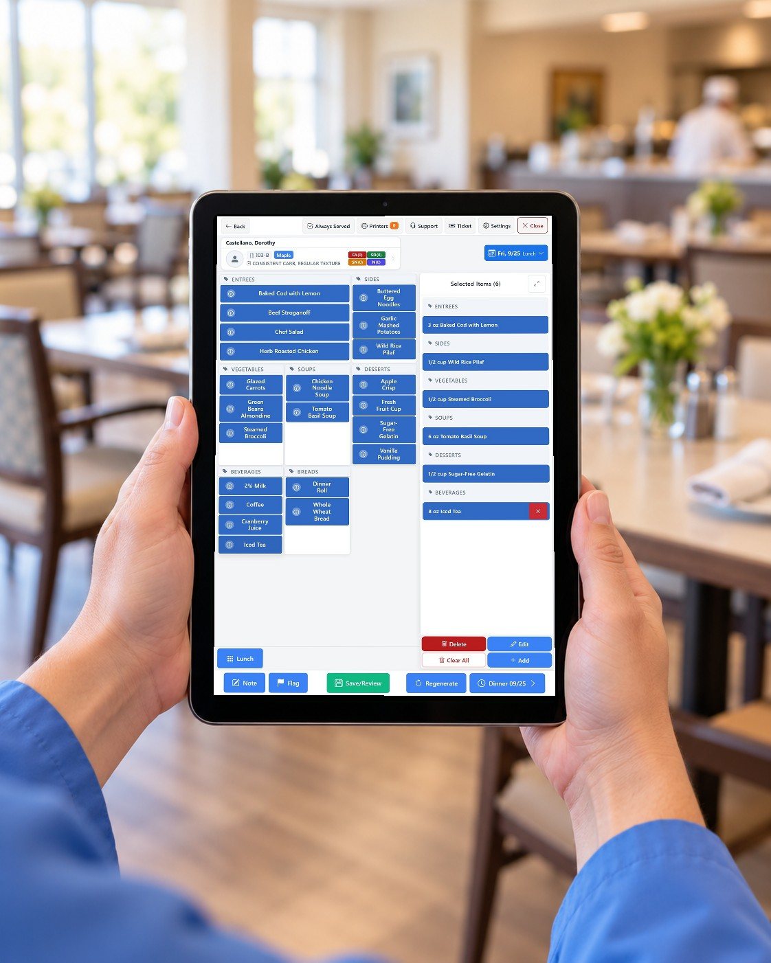 Hands holding a tablet upright in a dining room, showing Dietech Selective Touch lunch ordering with menu tiles and the selected items.